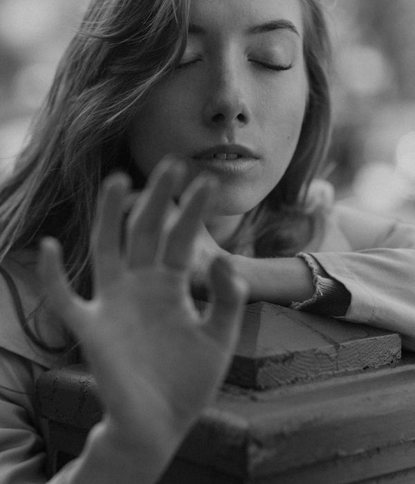 Woman in a calm yoga pose in a dark studio with golden light.